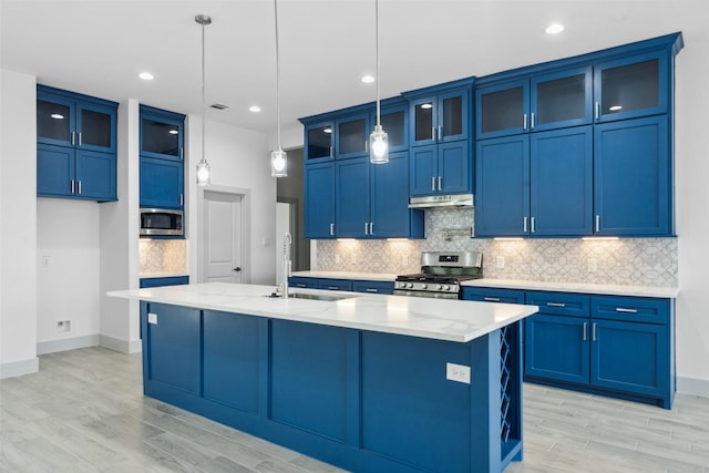kitchen with blue cabinetry, light wood-style flooring, stainless steel appliances, backsplash, and under cabinet range hood