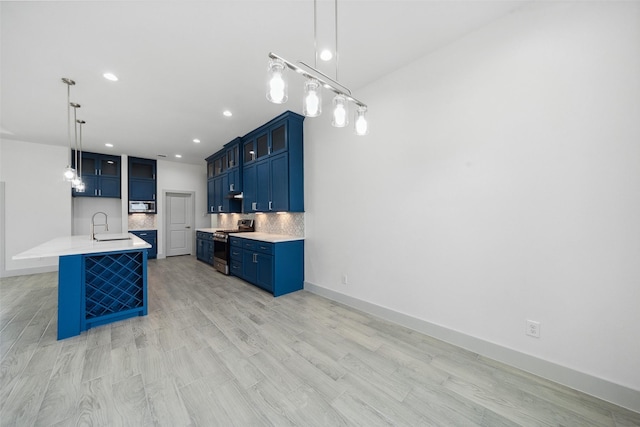 kitchen featuring a sink, stainless steel gas stove, light countertops, blue cabinetry, and decorative backsplash