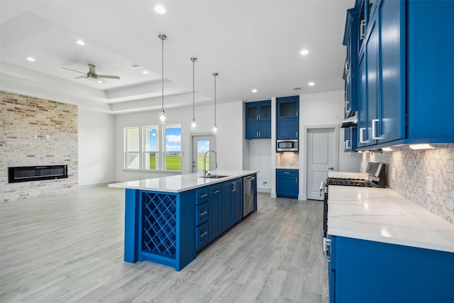 kitchen featuring ceiling fan, backsplash, appliances with stainless steel finishes, a sink, and light wood-style floors