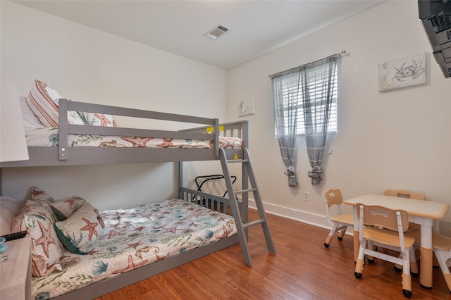 bedroom featuring baseboards, visible vents, and wood finished floors