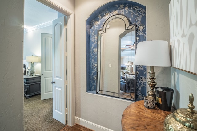 corridor with baseboards, carpet, and a textured wall