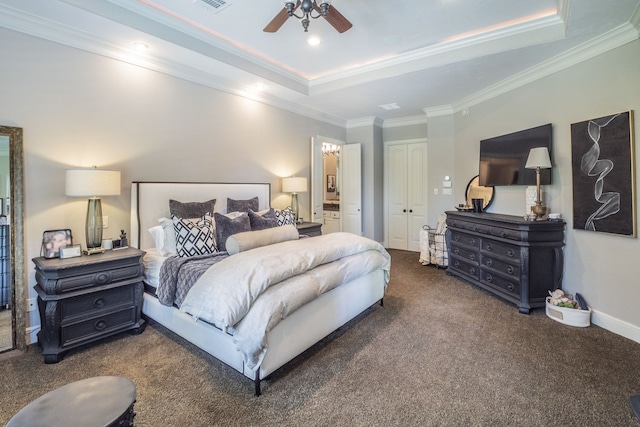 carpeted bedroom featuring a closet, ornamental molding, a tray ceiling, and visible vents