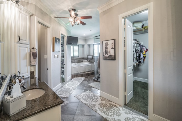 bathroom featuring vanity, ornamental molding, baseboards, ceiling fan, and a spacious closet