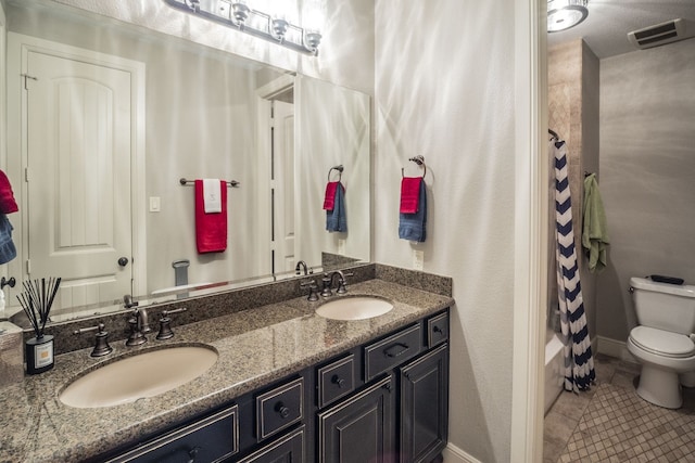 full bathroom featuring double vanity, toilet, a sink, and tile patterned flooring