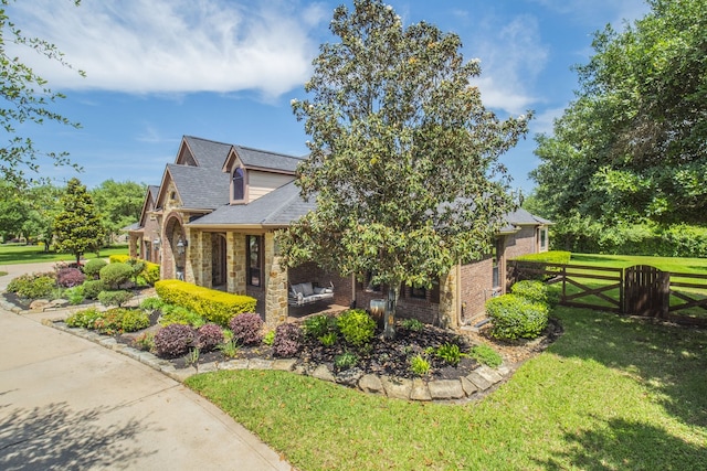 view of home's exterior featuring fence, stone siding, brick siding, a gate, and a lawn