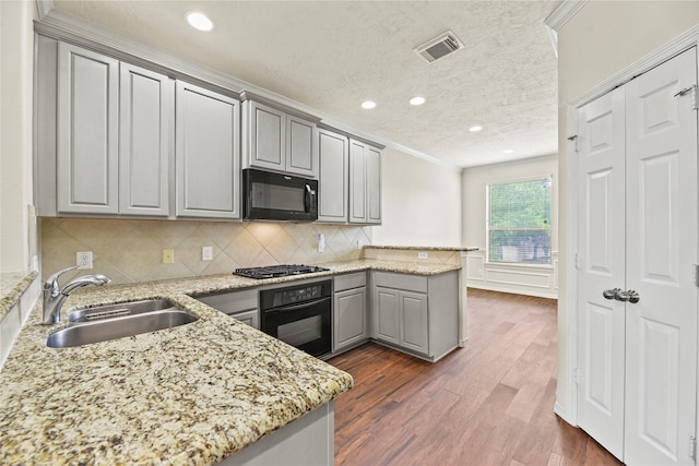 7824 Stoneyway Dr, Houston, TX 77040 - kitchen featuring a peninsula, light stone counters, a sink, black appliances, and gray cabinetry