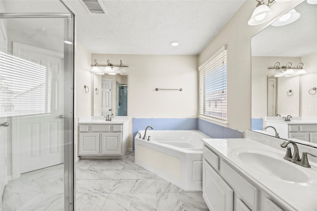 7824 Stoneyway Dr, Houston, TX 77040 - bathroom with visible vents, a garden tub, two vanities, a shower stall, and a sink