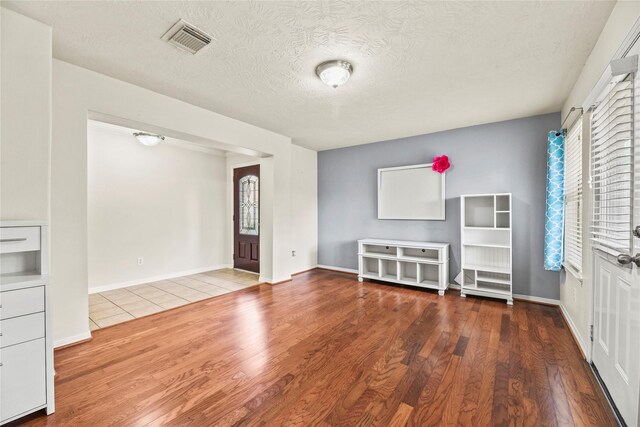 7824 Stoneyway Dr, Houston, TX 77040 - unfurnished living room with wood finished floors, plenty of natural light, a textured ceiling, and visible vents