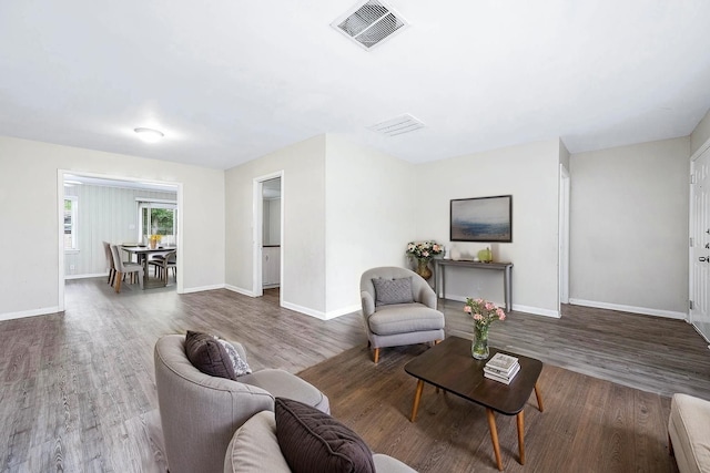 living room featuring baseboards, visible vents, and wood finished floors