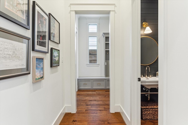 hallway with a sink, baseboards, and dark wood-style floors