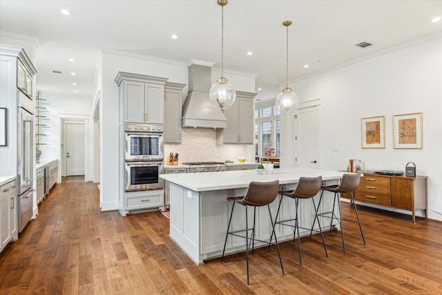 kitchen featuring visible vents, custom exhaust hood, light countertops, gray cabinetry, and stainless steel appliances