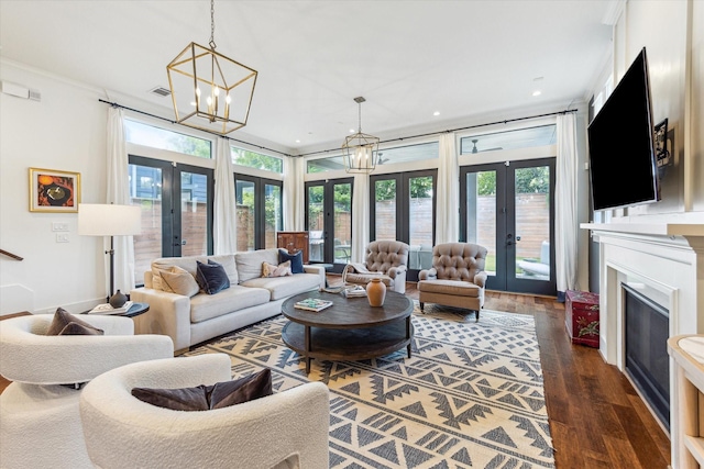 living area with an inviting chandelier, a fireplace, french doors, dark wood-type flooring, and visible vents