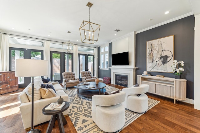 living room featuring a healthy amount of sunlight, crown molding, wood finished floors, and visible vents