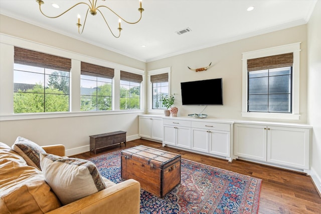 living room featuring visible vents, wood finished floors, baseboards, a notable chandelier, and ornamental molding