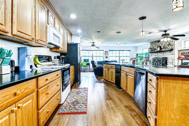 kitchen featuring ceiling fan, appliances with stainless steel finishes, dark countertops, open floor plan, and light wood-type flooring