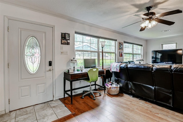 foyer with visible vents, a ceiling fan, crown molding, and a healthy amount of sunlight