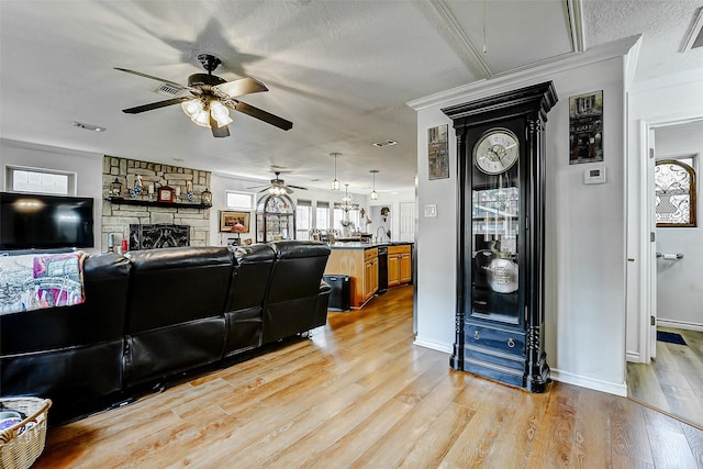 living area featuring light wood-style floors, ceiling fan, visible vents, and a stone fireplace