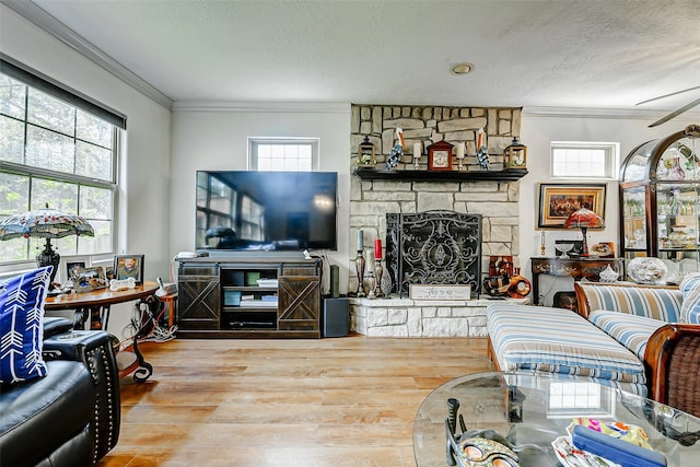 living room featuring ornamental molding, a textured ceiling, wood finished floors, and a fireplace