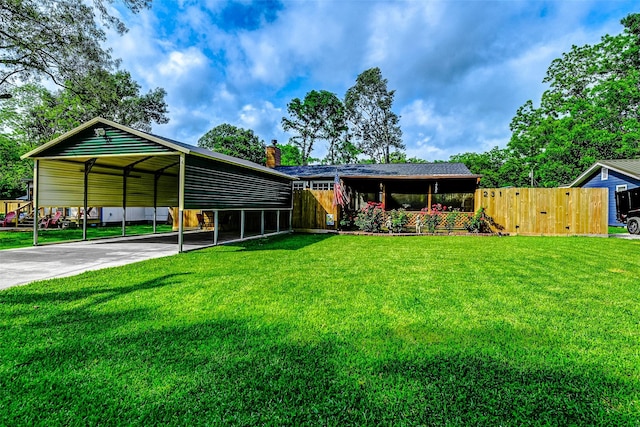 view of front facade with a detached carport, a front lawn, fence, a chimney, and driveway