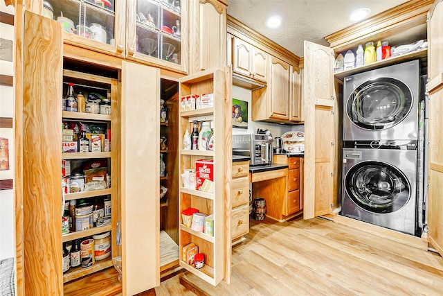 laundry area with recessed lighting, laundry area, light wood-type flooring, and stacked washer and clothes dryer