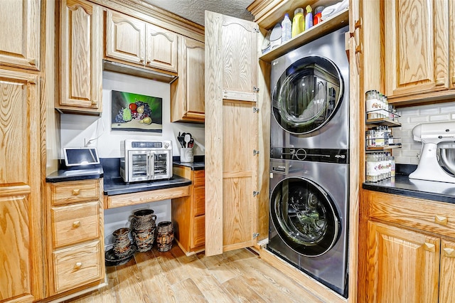 washroom with stacked washer and dryer and light wood finished floors