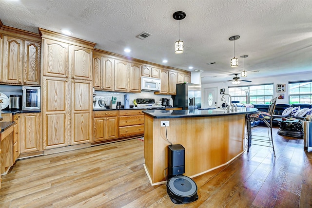 kitchen with visible vents, dark countertops, light wood-style floors, white microwave, and stainless steel fridge with ice dispenser