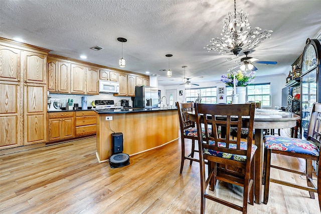 kitchen with a ceiling fan, visible vents, range, white microwave, and stainless steel fridge