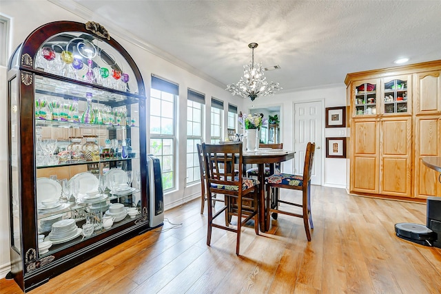 dining room featuring ornamental molding, light wood-type flooring, visible vents, and a chandelier