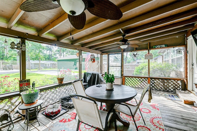 sunroom featuring a ceiling fan, beam ceiling, and a healthy amount of sunlight