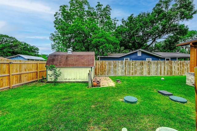 view of yard featuring a storage shed, an outdoor structure, and a fenced backyard