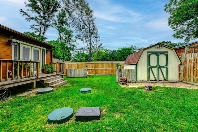 view of yard with a storage unit, a fenced backyard, a wooden deck, and an outdoor structure