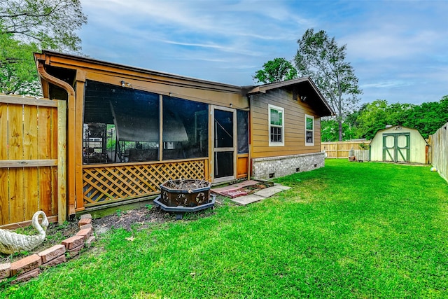 back of house featuring crawl space, a sunroom, a shed, a fenced backyard, and a yard