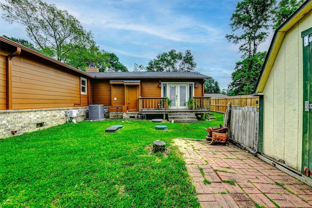rear view of house featuring a chimney, french doors, central air condition unit, fence, and a yard