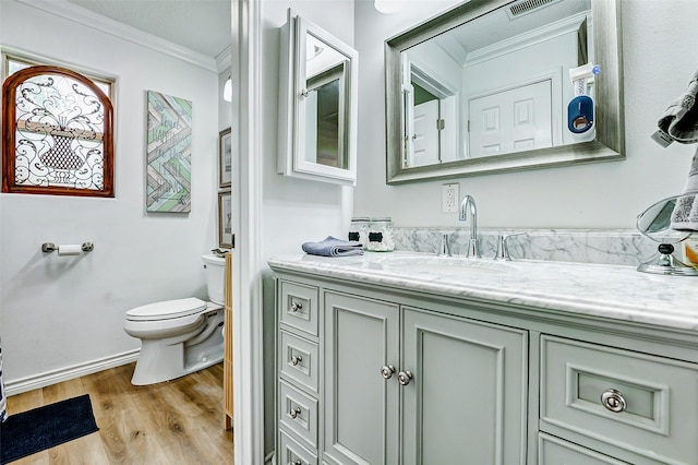 bathroom featuring crown molding, vanity, wood finished floors, toilet, and baseboards