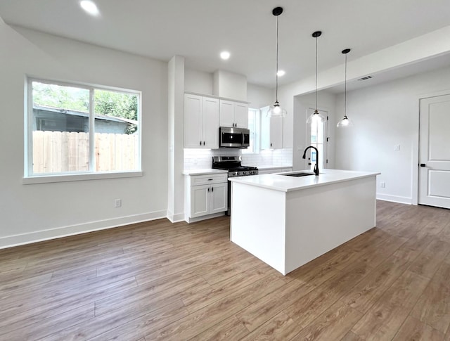 kitchen featuring backsplash, stainless steel appliances, white cabinets, and a sink