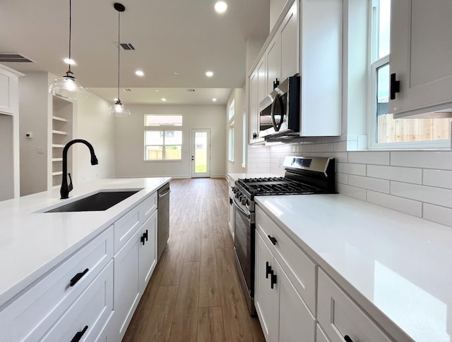 kitchen with hanging light fixtures, a sink, stainless steel appliances, recessed lighting, and dark wood-type flooring