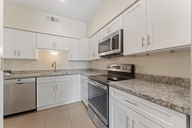 7545 Brompton St Unit 7545, Houston, TX 77025 - kitchen featuring appliances with stainless steel finishes, a sink, white cabinets, and light tile patterned floors
