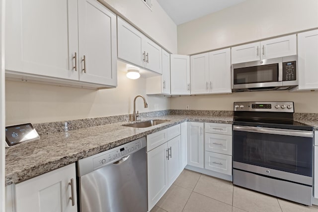 kitchen with a sink, white cabinetry, light tile patterned floors, and stainless steel appliances