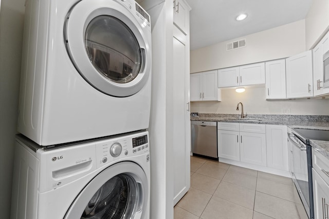 laundry area featuring visible vents, stacked washer / drying machine, recessed lighting, a sink, and light tile patterned floors