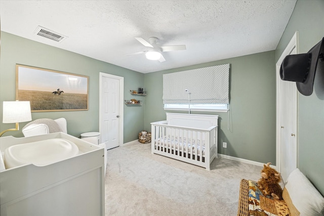 bedroom with carpet flooring, a textured ceiling, a ceiling fan, baseboards, and visible vents