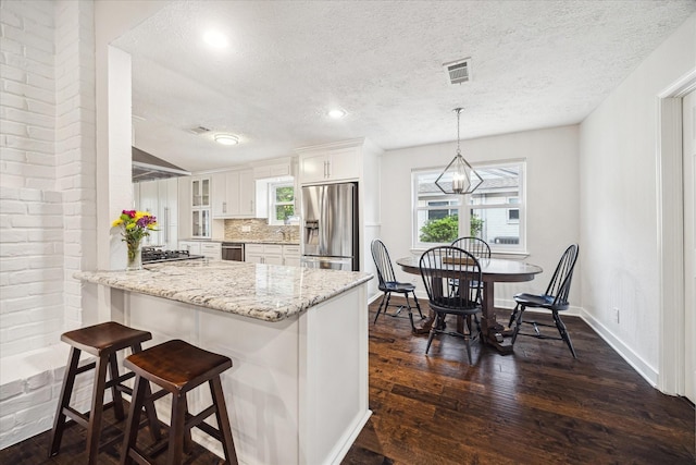 kitchen featuring a textured ceiling, white cabinets, tasteful backsplash, and stainless steel appliances