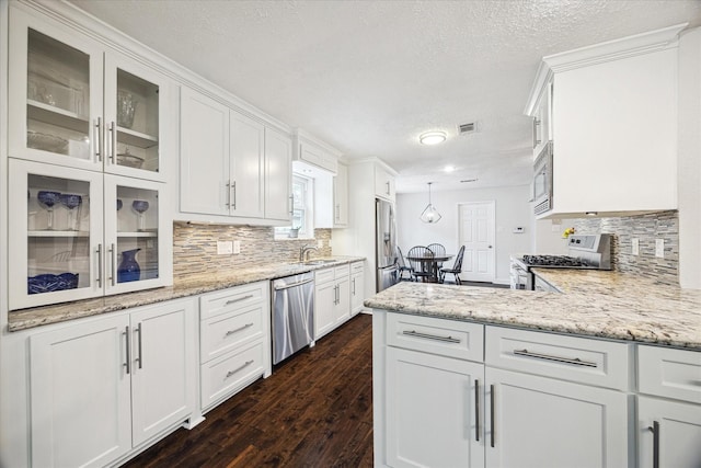 kitchen with a textured ceiling, visible vents, dark wood finished floors, white cabinets, and stainless steel appliances