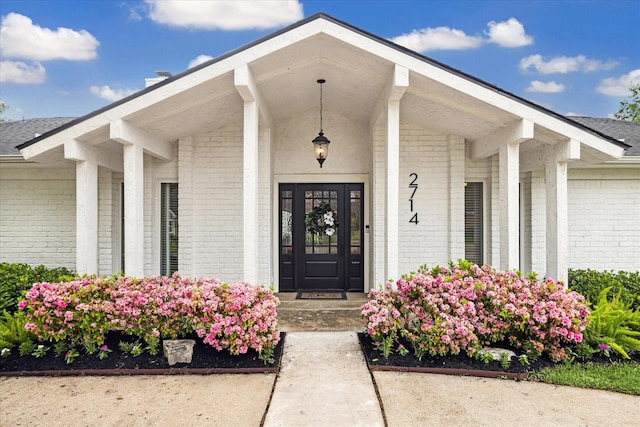doorway to property featuring a porch and brick siding
