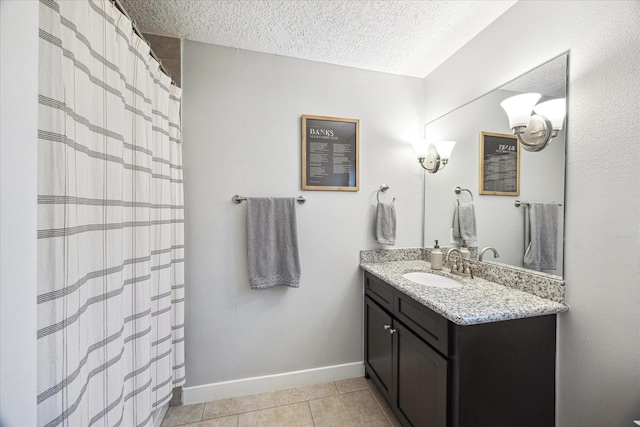 full bath featuring tile patterned flooring, a textured ceiling, baseboards, and vanity