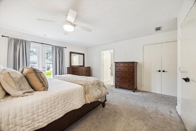 bedroom with visible vents, ensuite bathroom, light colored carpet, a textured ceiling, and a ceiling fan
