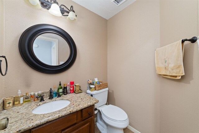 bathroom featuring vanity, baseboards, visible vents, and toilet