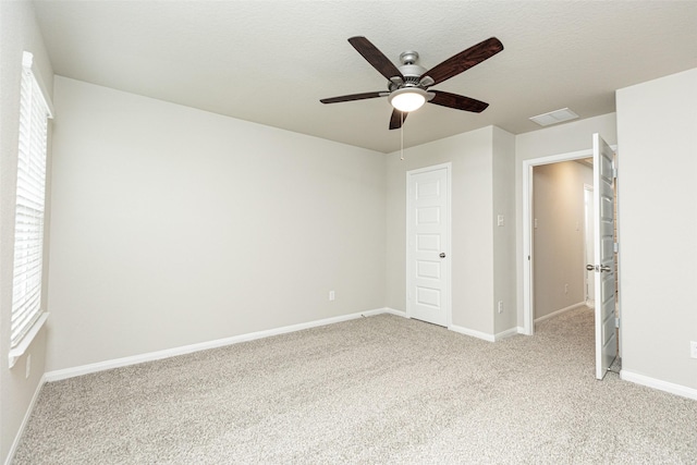 unfurnished bedroom with light colored carpet, baseboards, visible vents, and ceiling fan