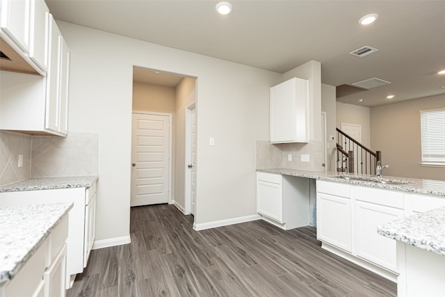 kitchen featuring backsplash, visible vents, light stone countertops, white cabinets, and dark wood-type flooring