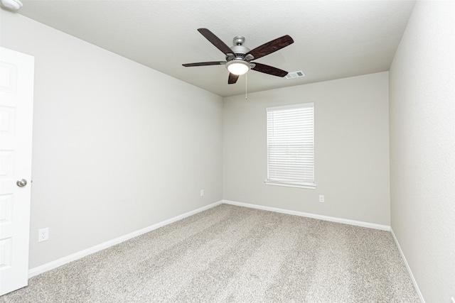carpeted spare room featuring visible vents, baseboards, and ceiling fan
