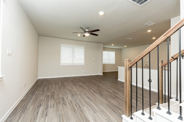 unfurnished living room featuring visible vents, baseboards, ceiling fan, and wood finished floors